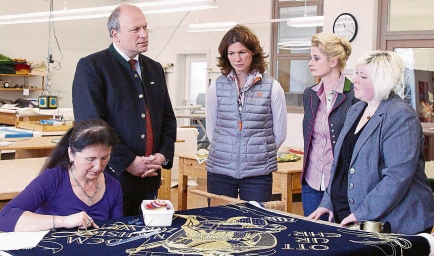 Landrätin Tanja Schweiger (Mitte) und Bürgermeister Christian Kiendl (2. von rechts) machten sich bei einem Besuch von Fahnen Kössinger selbst ein Bild vom Traditionshandwerk Fahnenstickerei